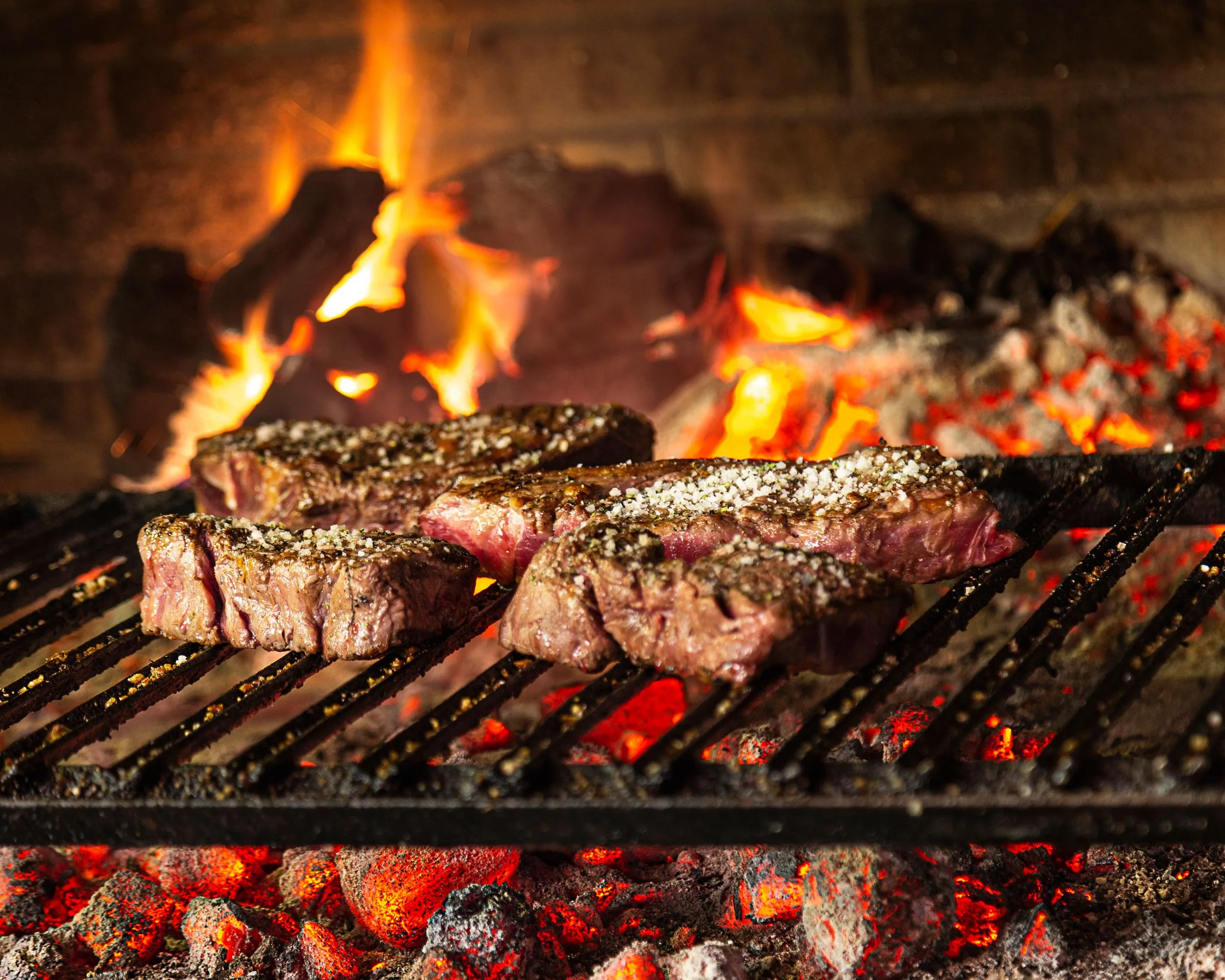 Txuletas de vaca vieja sobre la parrilla de carbón, con las brasas al rojo vivo debajo